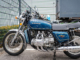 Blue vintage motorcycle in parking lot.